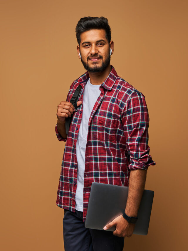 smiling-indian-man-casual-close-with-laptop-backpack-pastel-wall